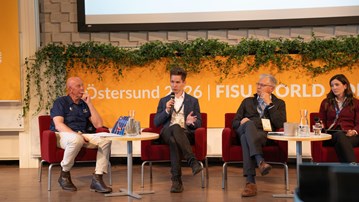 4 personer på en scen i ett panelsamtal. Joakim håller i en mikrofon och pratar.