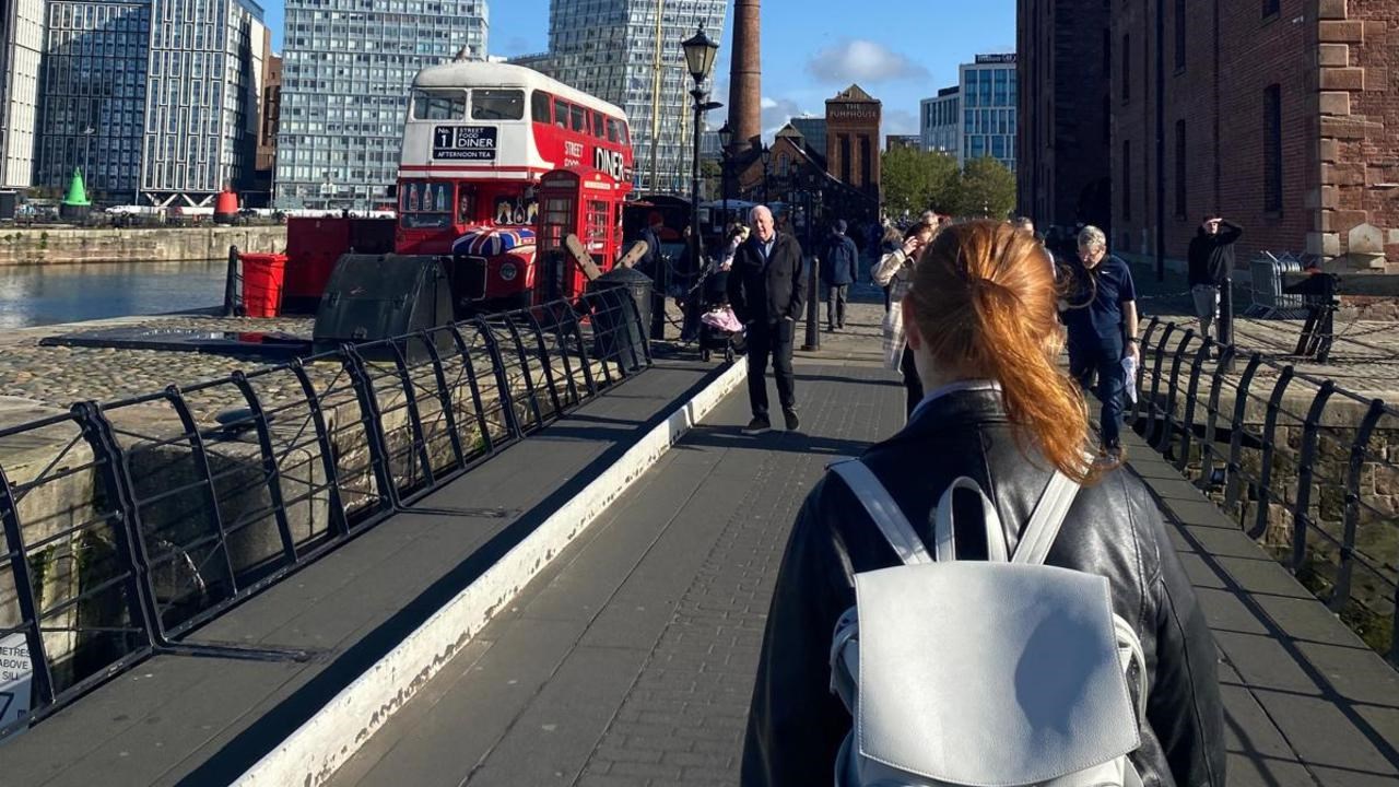 En kvinna med ryggsäck går över en bro.