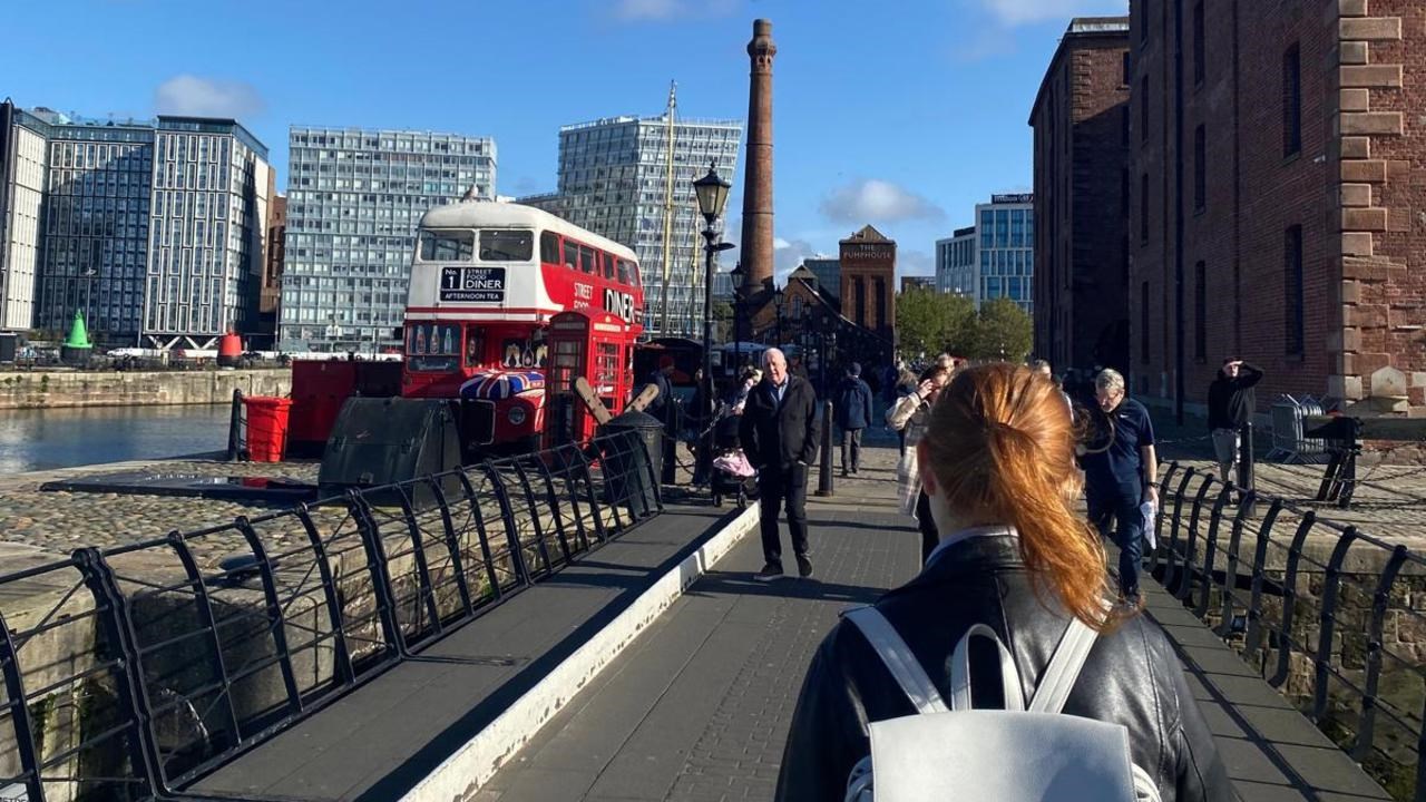 En kvinna med ryggsäck går över en bro.