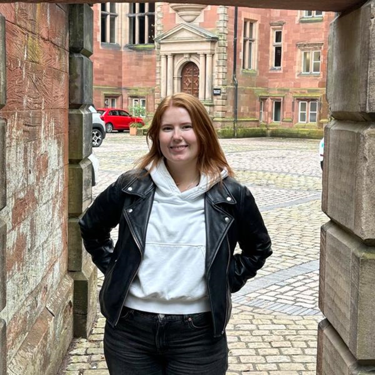 En kvinna står framför en grind.