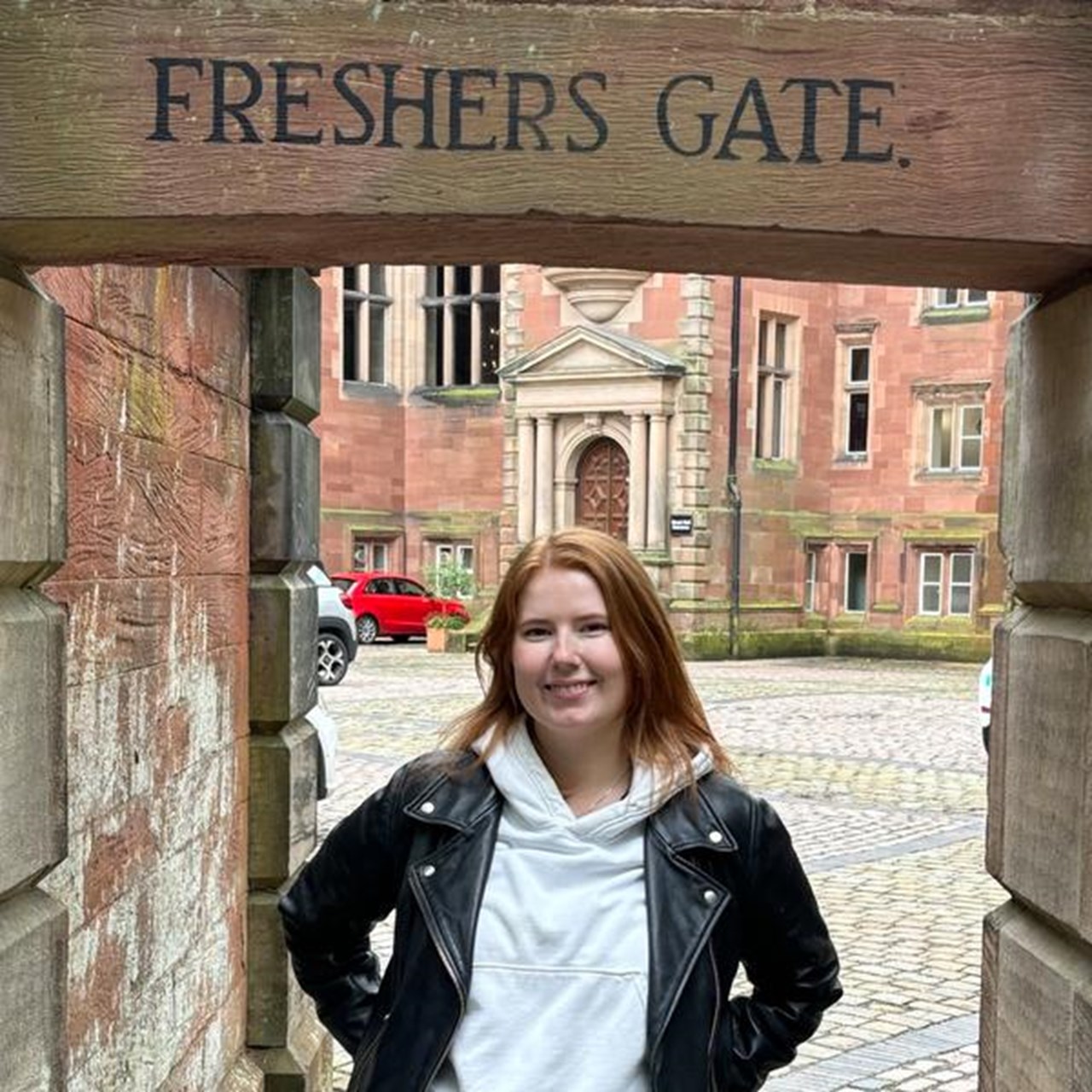 En kvinna står framför en grind.