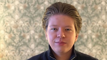 Hugo Sidenhag sitter framför en tapetserad vägg.