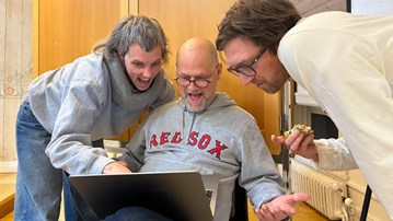 Två män och en kvinna tittar på en laptopskärm.