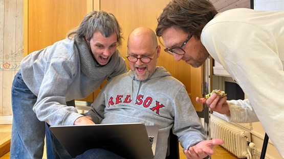 Två män och en kvinna tittar på en laptopskärm.