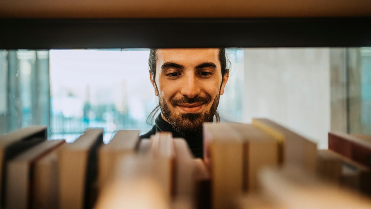 Man kollar böcker i en bibliotekshylla.
