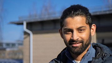 En man med skägg står framför en byggnad på Umeå universitet.