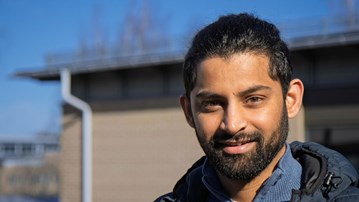 En man med skägg står framför en byggnad på Umeå universitet.