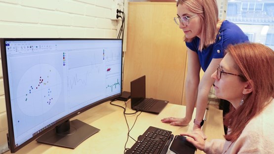 Two female researchers are looking at a computer screen.