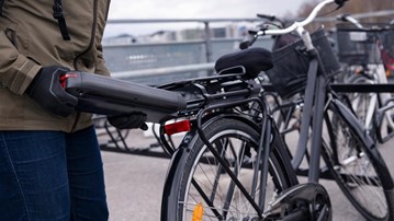 Person som sätter in ett batteri i en elcykel