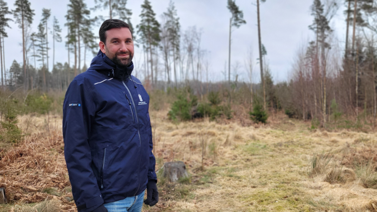 Joel Avenius stående med skogsmark i bakgrunden