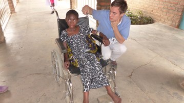 Manlig sjuksköterska på knä bredvid flicka i rullstol