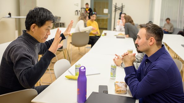 Jian-Feng Mao and Cemal Erdem sit across from each other at a white table and discuss.