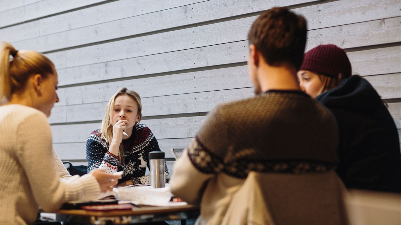 Studenter sitter runt ett bord och pratar