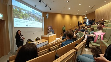 Overview of the auditorium, with Annika Egan Sjölander in front of a powerpoint