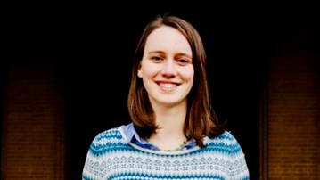 Foto av talaren Merel Semeijn stående framför en tegelvägg
