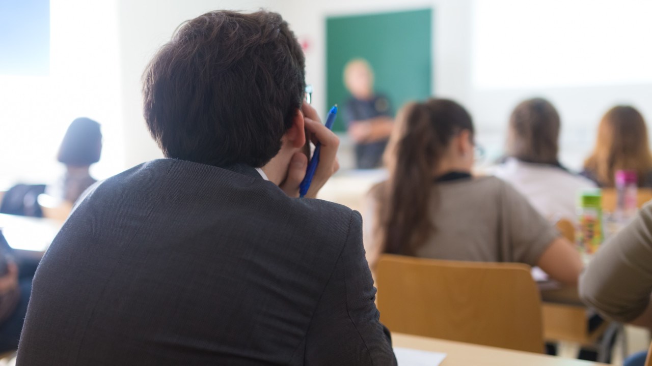 Ungdomar i klassrum lyssnar på lärare som undervisar.