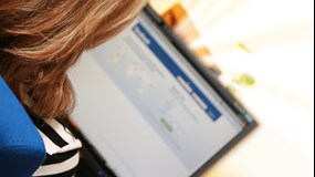 Person som loggar in på Facebook med sin laptop.