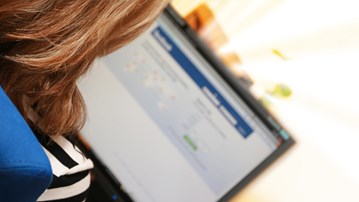 Person som loggar in på Facebook med sin laptop.