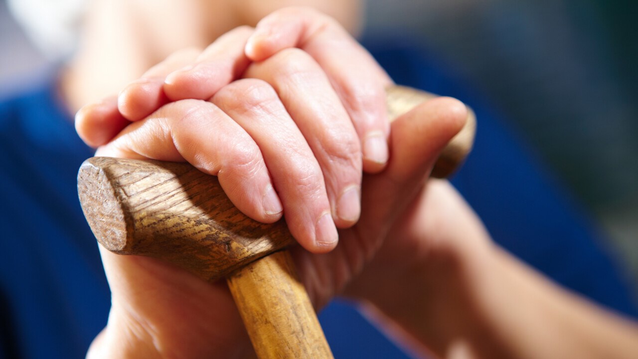 Elderly woman's hand on a cane.