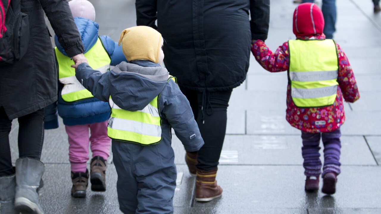Förskolebarn på promenad med gula västar på.