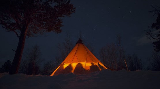 Persons gathered in a traditional Sámi tent.