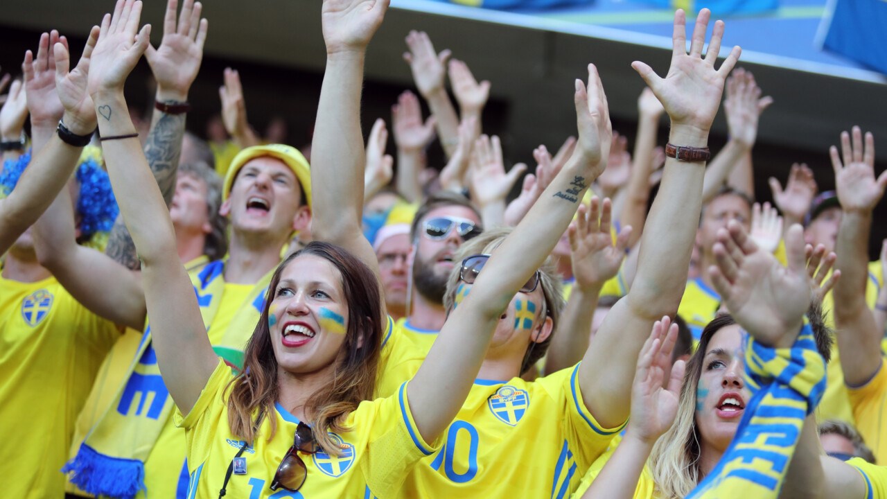 Svenska fotbollsfans med blågula kläder och ansiktsmålningar visar sitt stöd under en fotbollsmatch mellan Sverige och Belgien 2016.