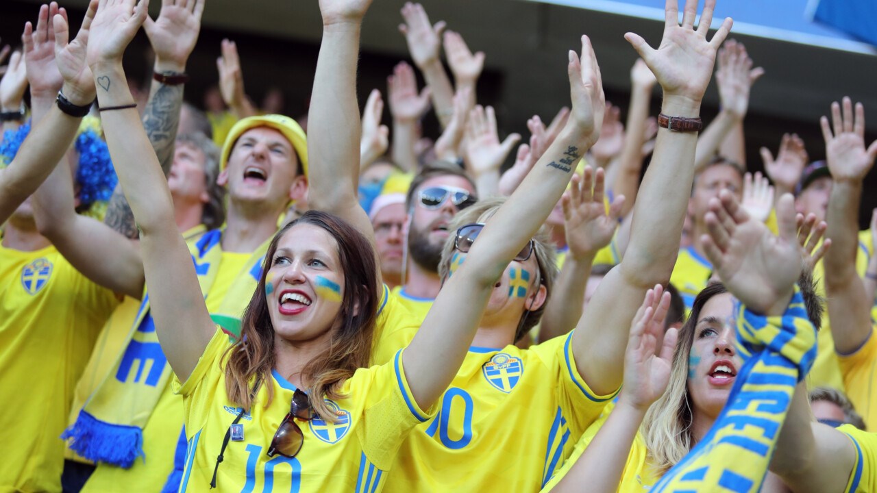 Svenska fotbollsfans med blågula kläder och ansiktsmålningar visar sitt stöd under en fotbollsmatch mellan Sverige och Belgien 2016.
