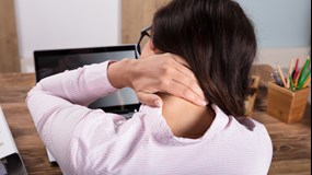 Kvinna vid dator som har ont i nacken