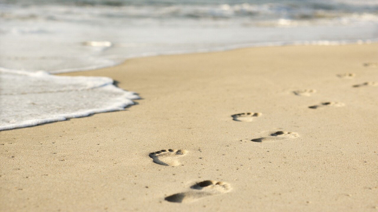 Fotspår i sanden på en strand.