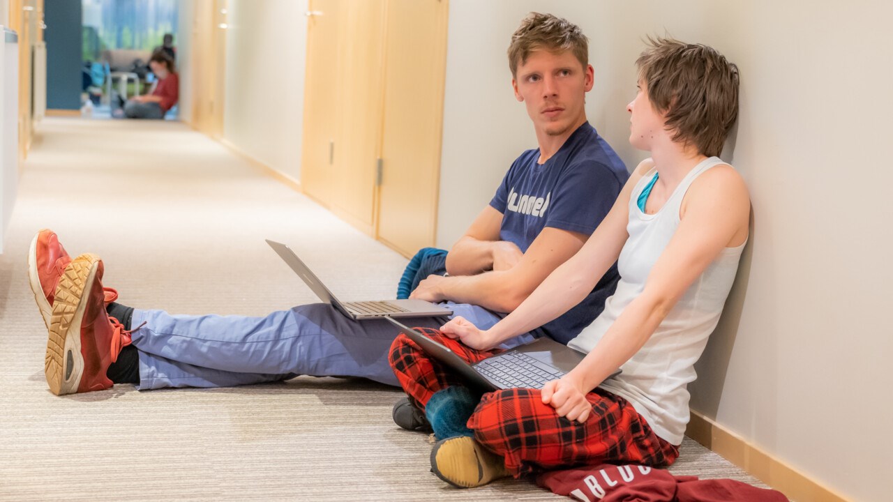 Bild på två deltagare i IceLab Camp sittande i en korridor