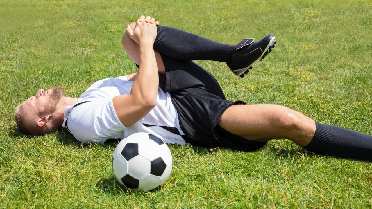 Fotbollsspelare som ligger med skadat knä