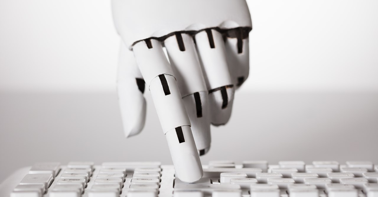 Närbild av robothand som trycker på ett tangenbord.