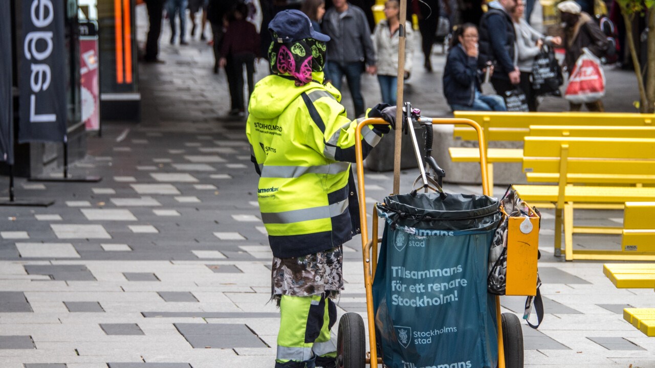 Person som plockar skräp från en gågata.