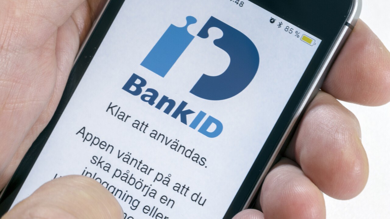 Hand med mobiltelefon där appen för mobilt bank-id visas.