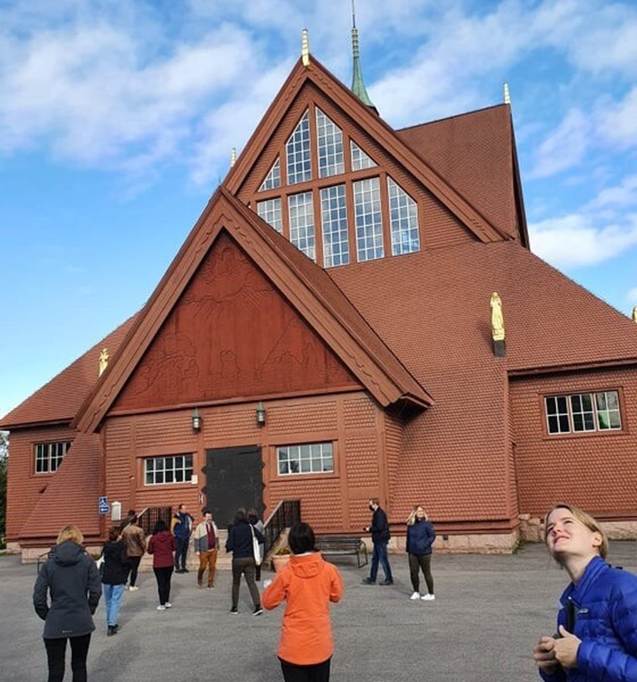 Picture of Kiruna church in the background and against it walks a group of doctoral students looking around