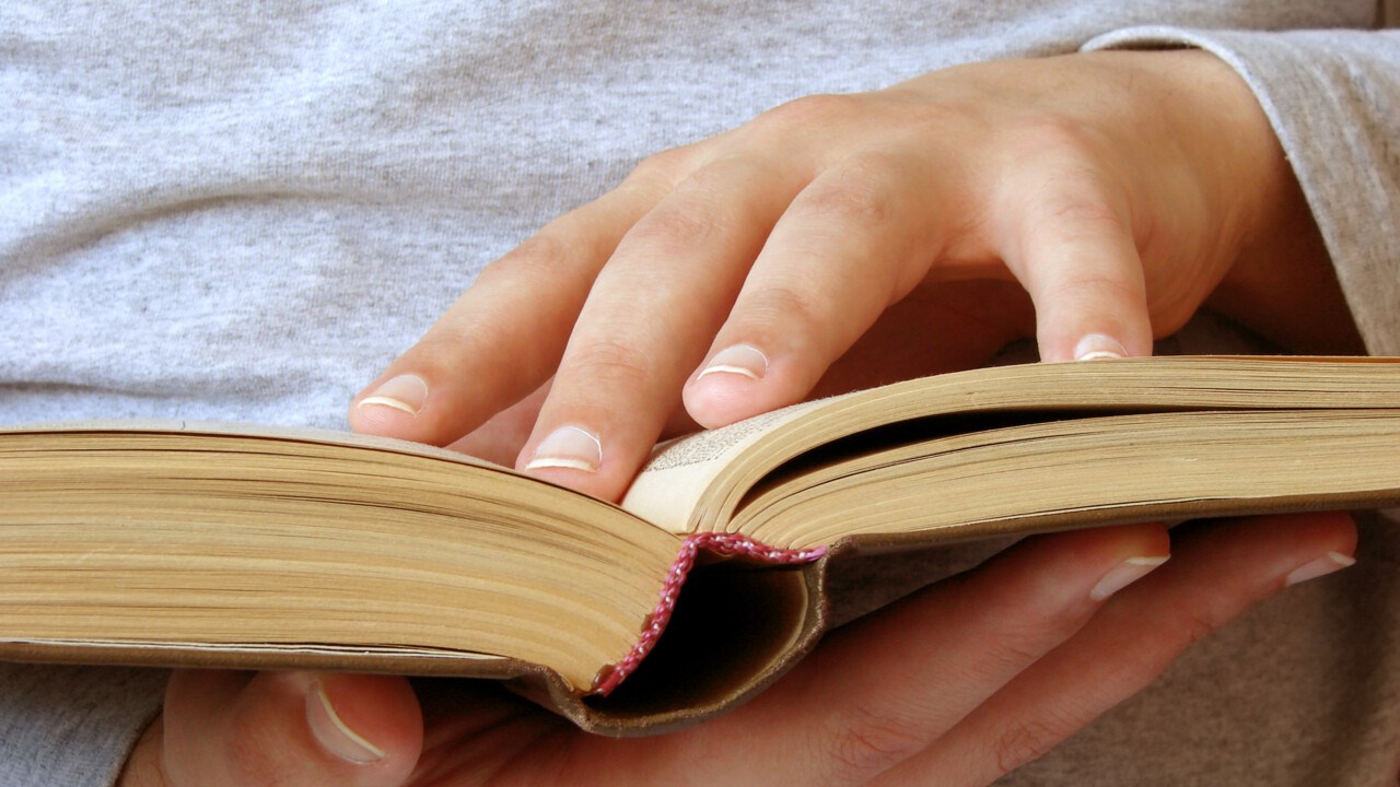 Händer som håller en öppen bok.