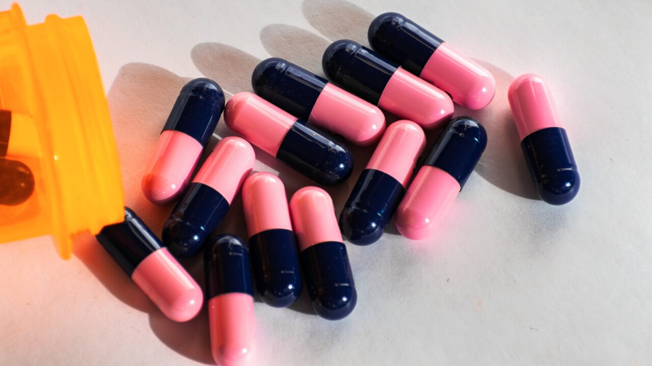 Närbild på rosa och blå antibiotikatabletter.