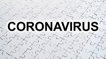 Ordet Coronavirus skrivet ovanpå ett vitt pussel.