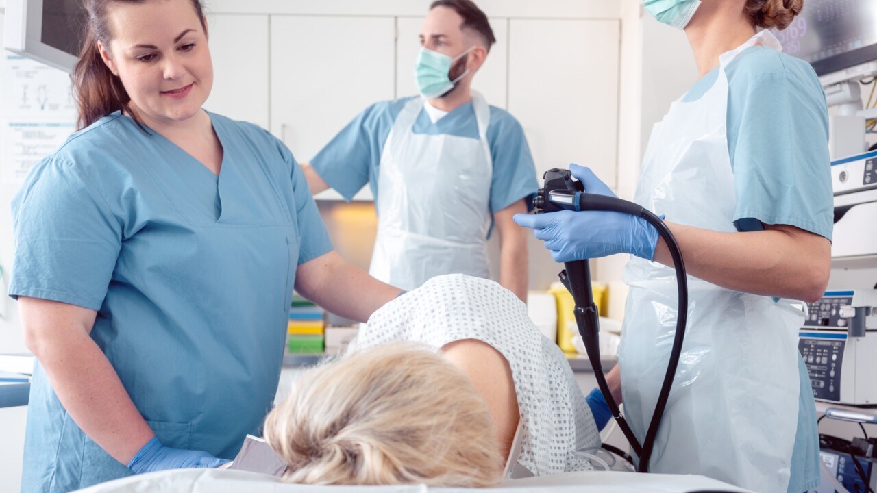 Patient ligger på brits medan sjukvårdspersonal genomför koloskopi