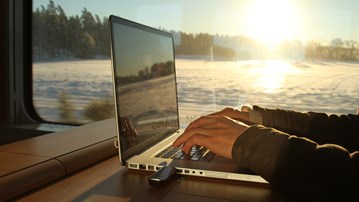 Foto av en person som arbetar vid en bärbar dator på ett tåg