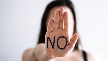 Woman holding up a hand where it is written "stop".