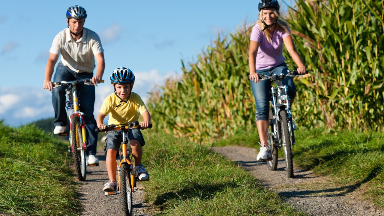 En familj med mamma, pappa och barn cyklar.