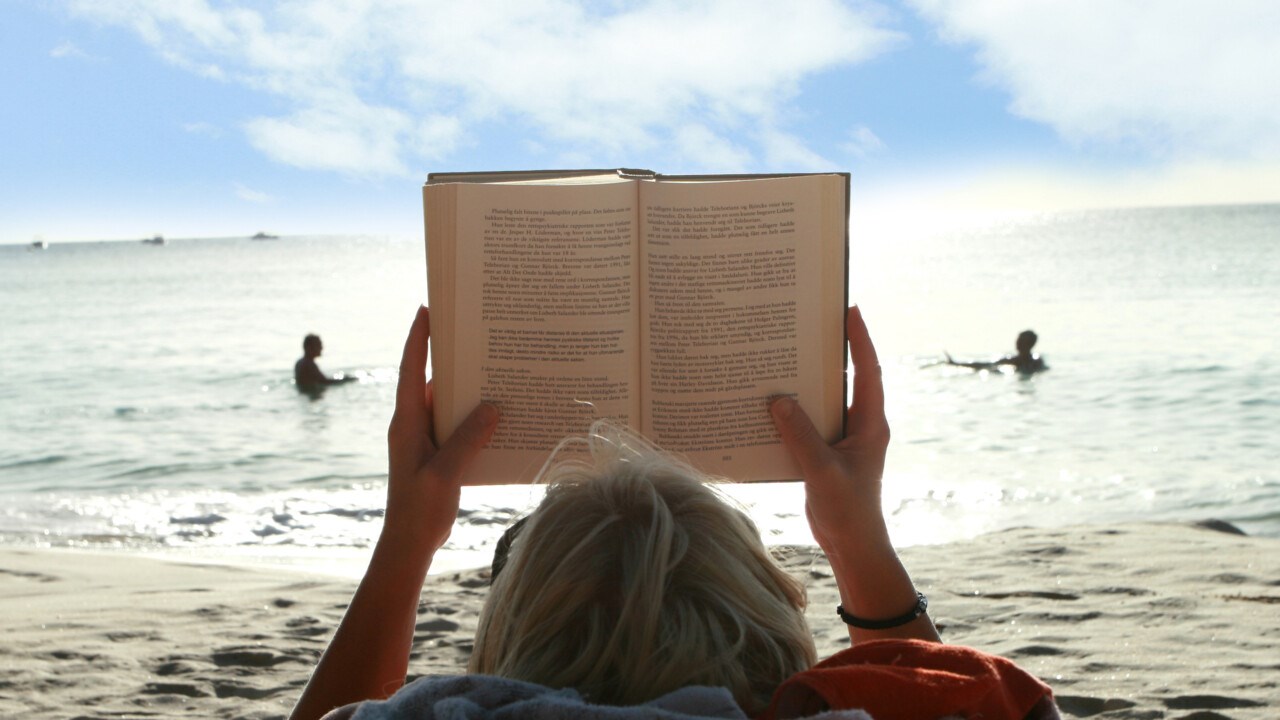 Bild på bokläsare på strand