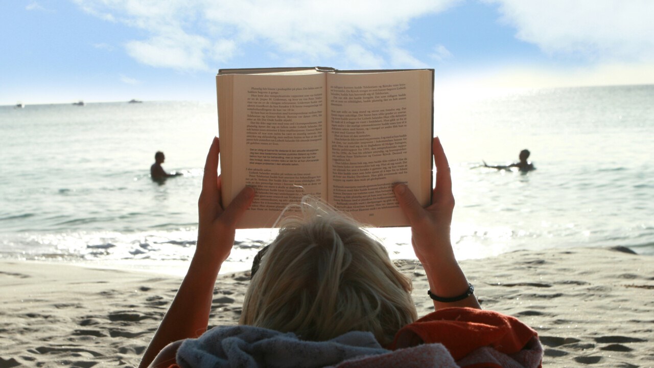 Bild på bokläsare på strand