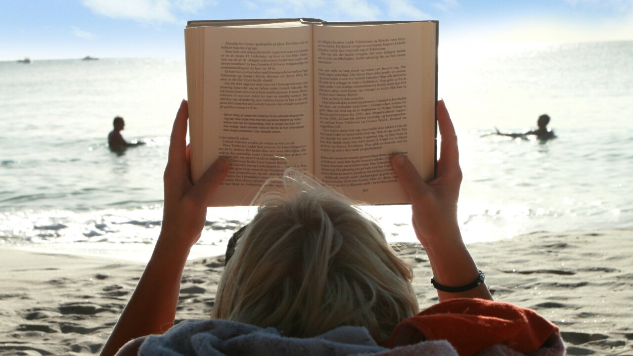 Bild på bokläsare på strand