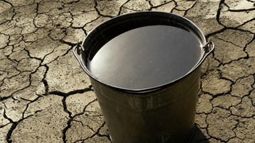 Hink med vatten på söndertorkad mark som illustration av klimatförändringarna