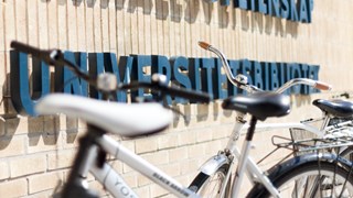 Universitetsbibliotekets fasad med skylt och cyklar i förgrunden.