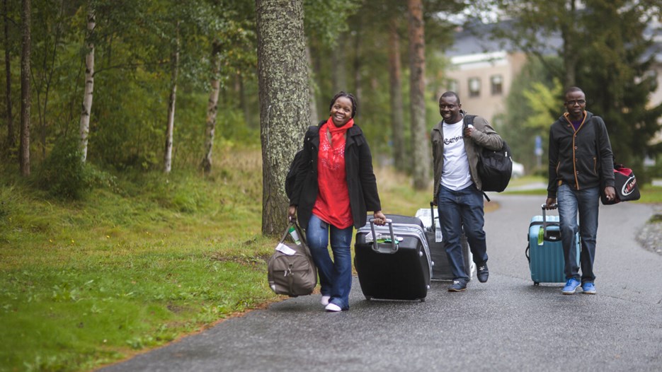 Tre vuxna personer som går med väskor på väg till sina nya lägenheter.