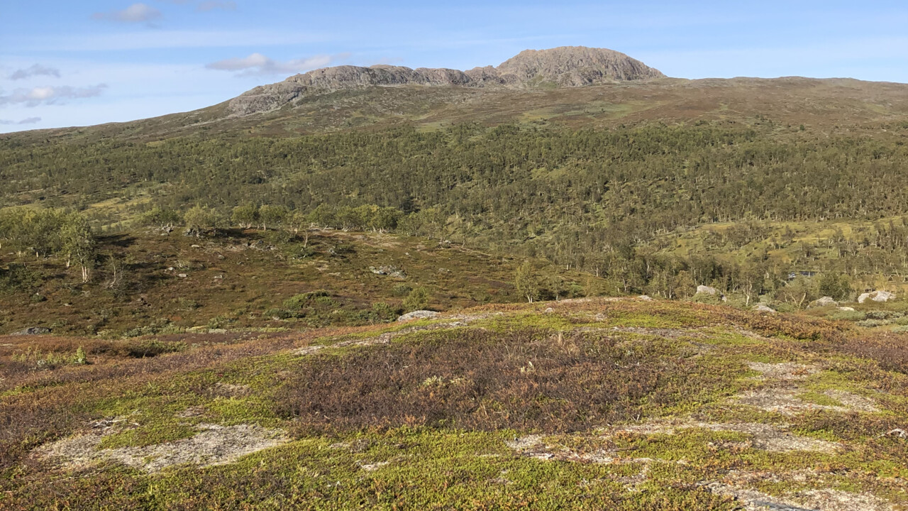 Photograph of the mountain Autoklimpen a stállo-foundation as a darker indentation in the foreground