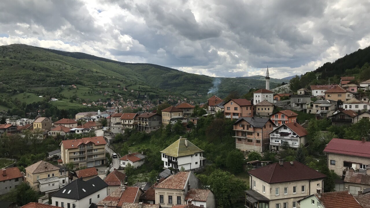 Flertalet små hus i Bosnien, skog och berg i bakgrunden